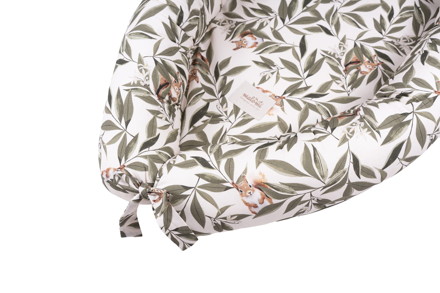 Detailopname van het Woodland babynestje met eekhoornprint en groene bladeren. Zichtbaar zijn de zachte opstaande randen, een striksluiting en het label “Malomi”.