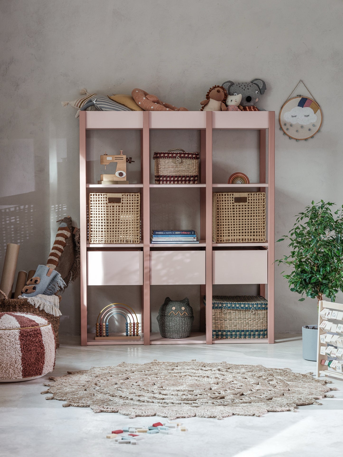 De charmante Tweens boekenkast in roze, volledig ingericht in een sfeervolle kinderkamer. De planken en lades zijn gevuld met boeken, speelgoed, manden en decoraties, wat de veelzijdigheid van dit opbergmeubel toont