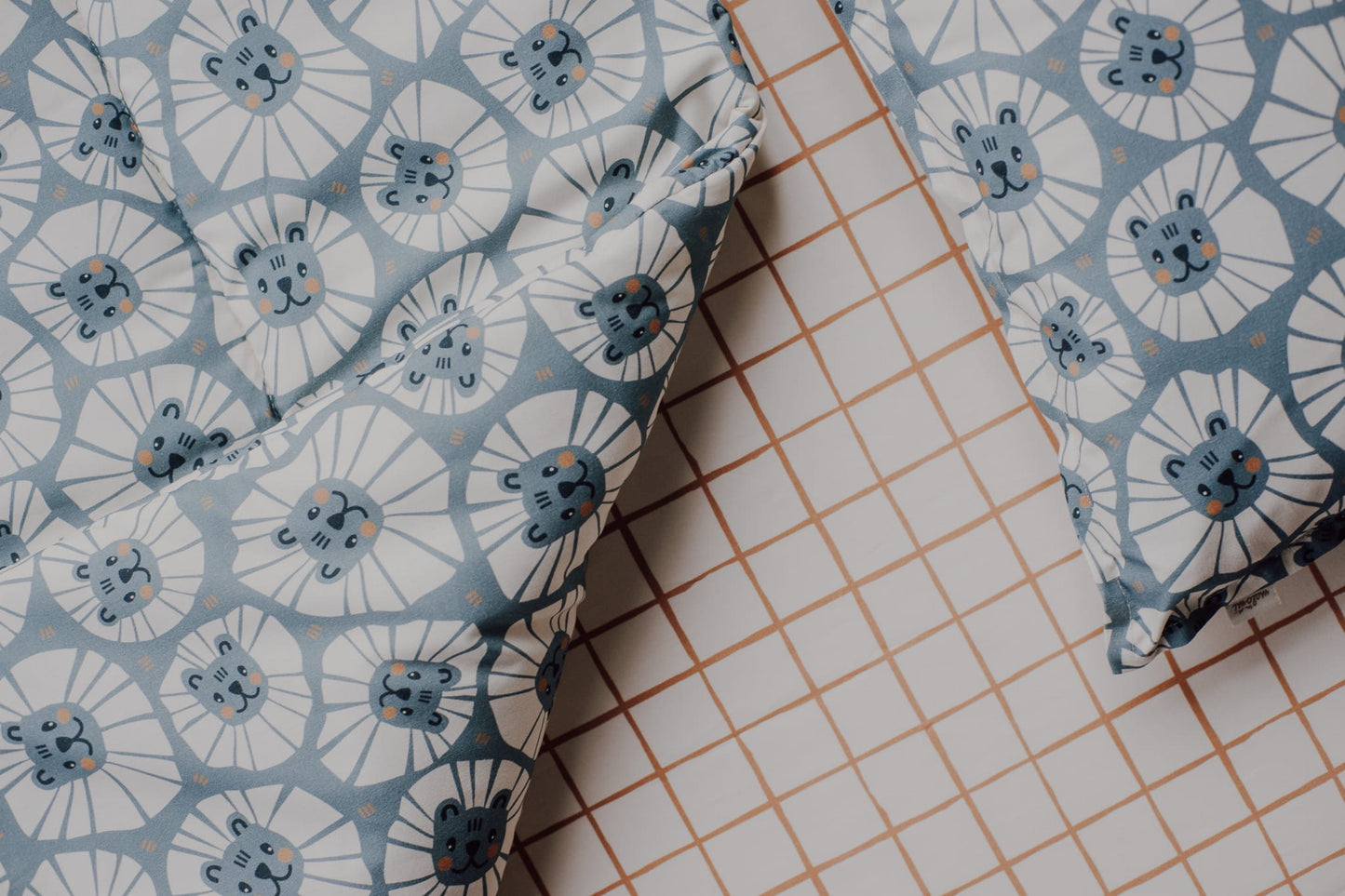Detail van denim leeuwen beddengoed met rasterkussen op achtergrond.