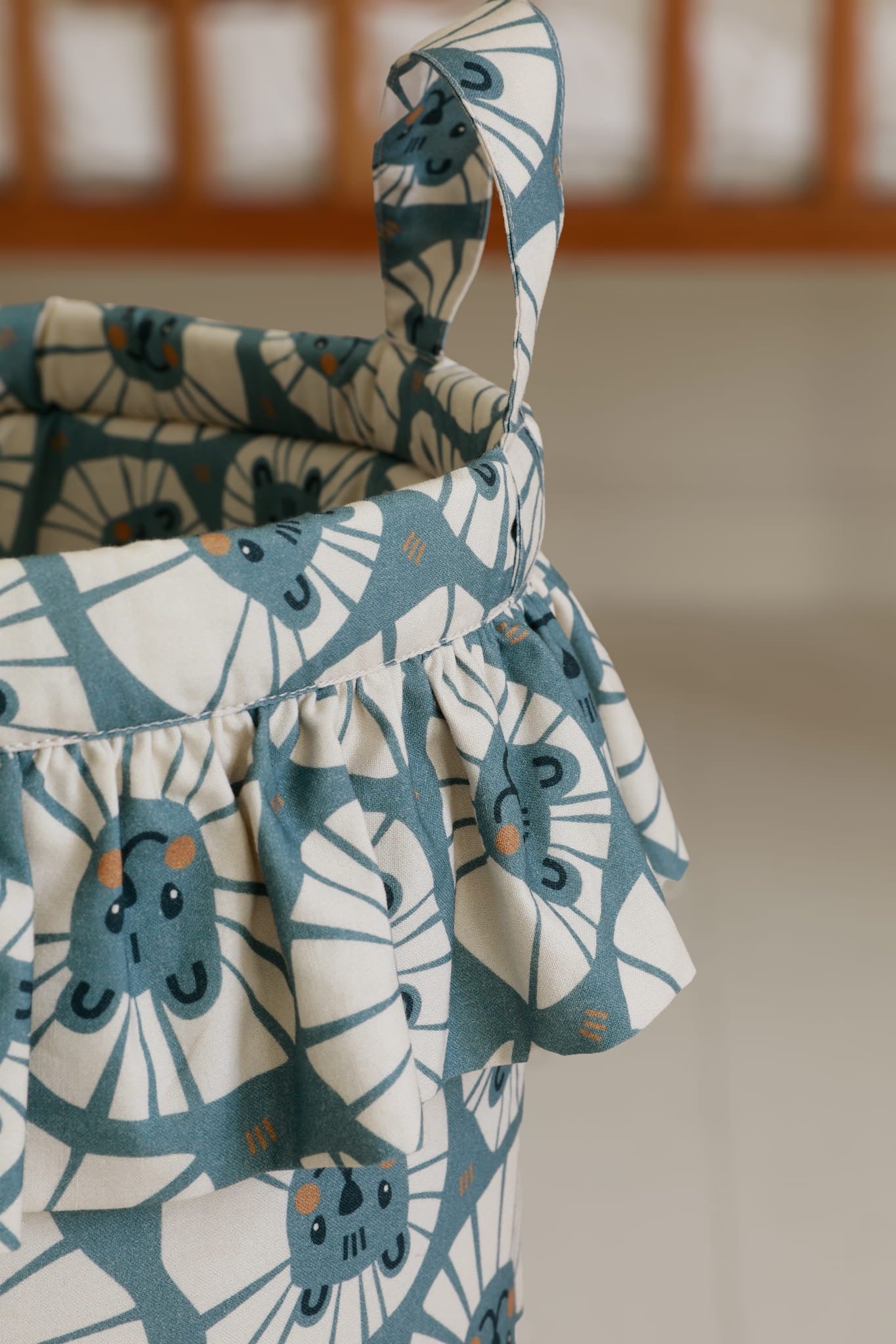 Detail van volant en Malomi-label op speelgoedmand met denim leeuwenprint