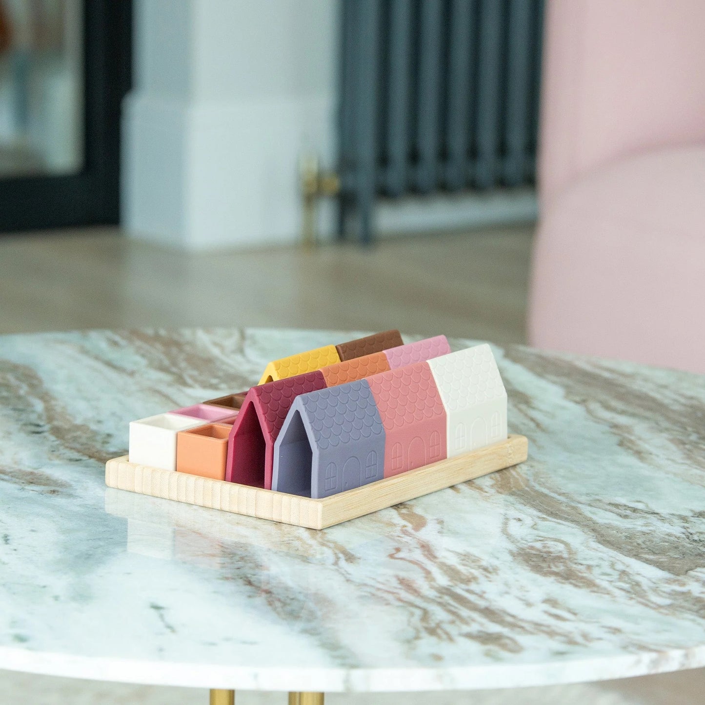 Neatly arranged colorful silicone toy houses and open cubes in a bamboo tray, viewed from an elevated angle against a light background