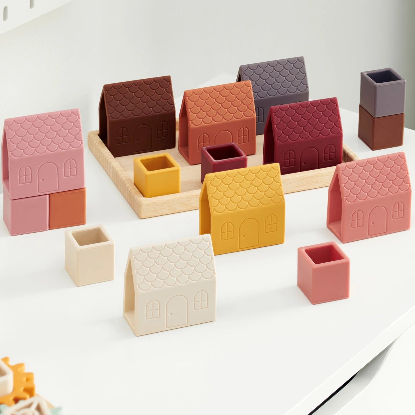Silicone toy houses and cubes in various colors neatly arranged in a bamboo tray on a marble coffee table