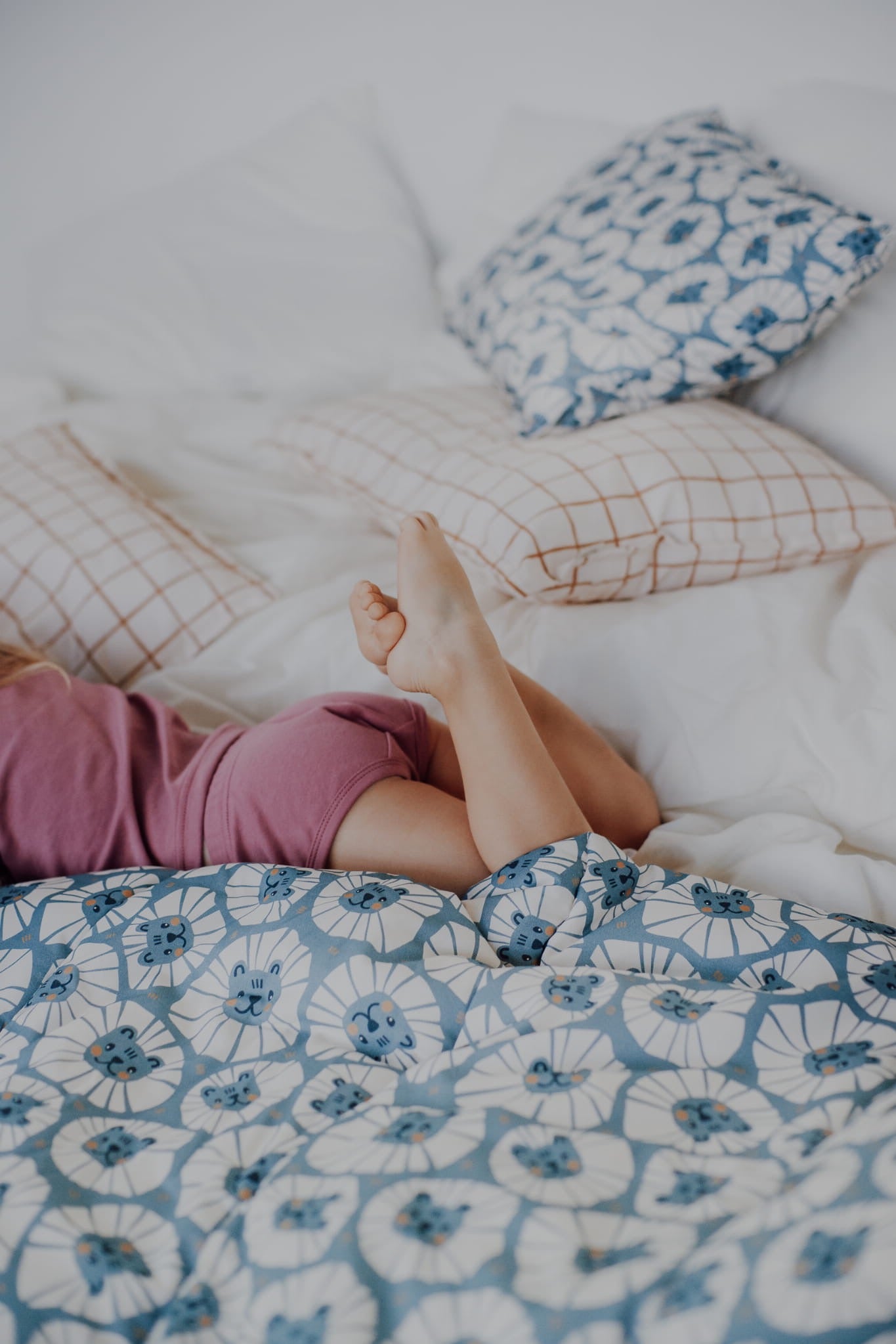 Kind ligt ontspannen op een bed met denimblauw leeuwen beddengoed van katoen.