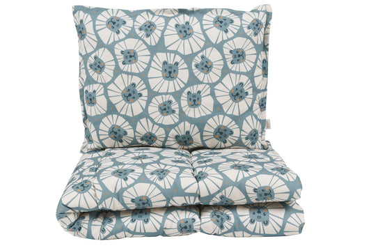 Set kussen en deken rechtop geplaatst, met speelse denim leeuwenpatroon.