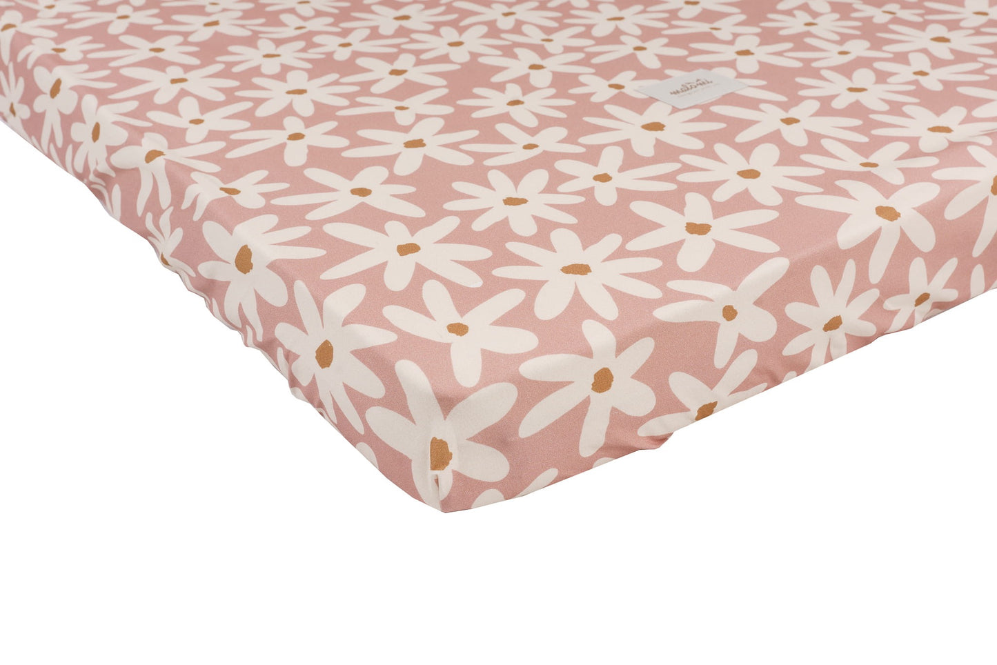 Blushroze hoeslaken met speelse witte bloemen, strak om een kindermatras gespannen – detailopname van de pasvorm en het patroon.