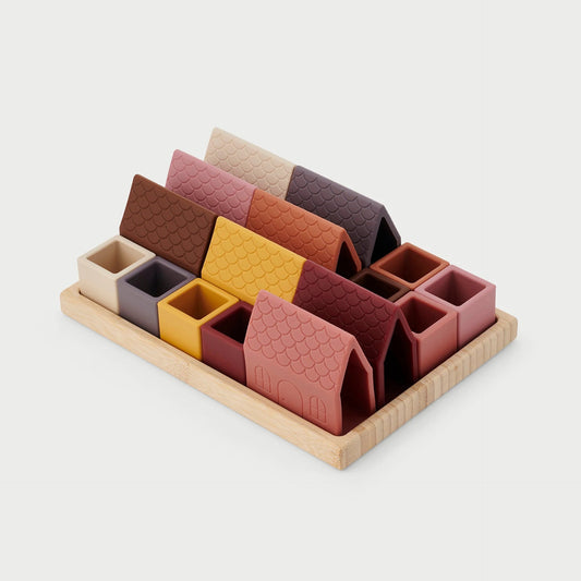 Colorful silicone toy houses and open cubes arranged on a white surface with a bamboo tray in the background