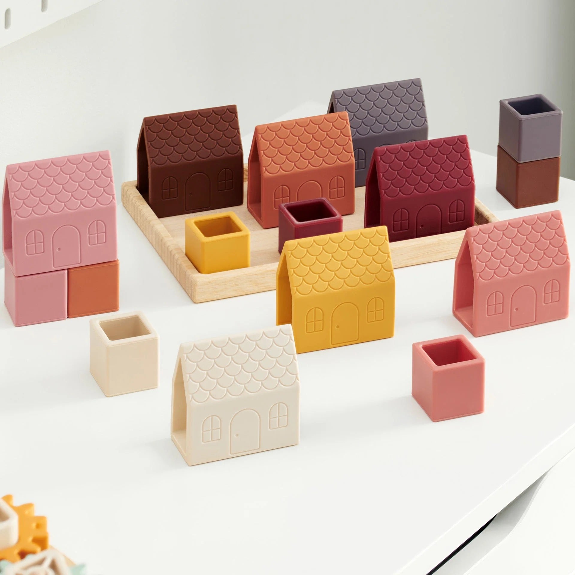 Silicone toy houses and cubes in various colors neatly arranged in a bamboo tray on a marble coffee table
