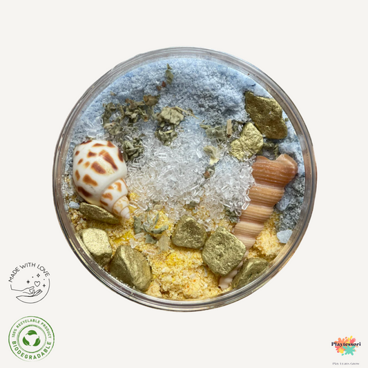 Een potje met de Bruisende Botanicals: Zee Schuim mix. De mix is blauw en geel en bevat echt zand, goudkleurige stenen en schelpen.