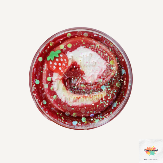 Een potje Little Munchkins Strawberry Sweetness speelklei, met een rood en wit gemarmerd deeg, glitters en een aardbeibedel aan de buitenkant.